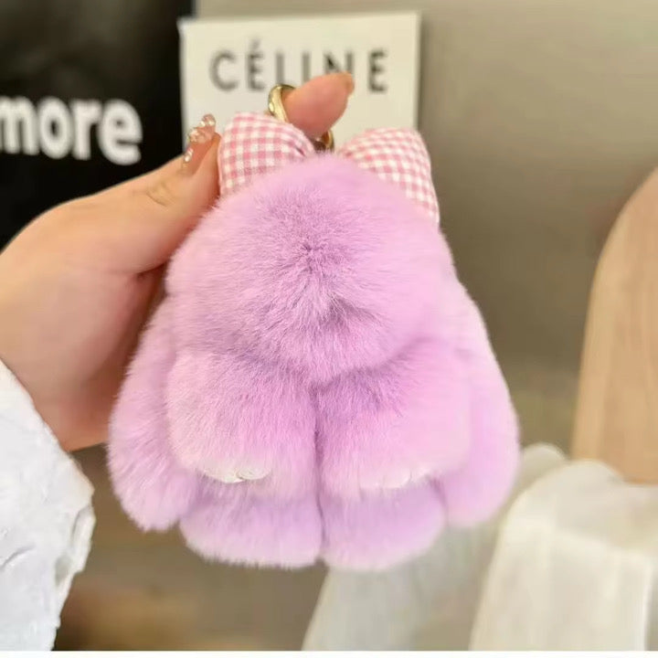 Purple fluffy keychain held by a hand with a blurred background