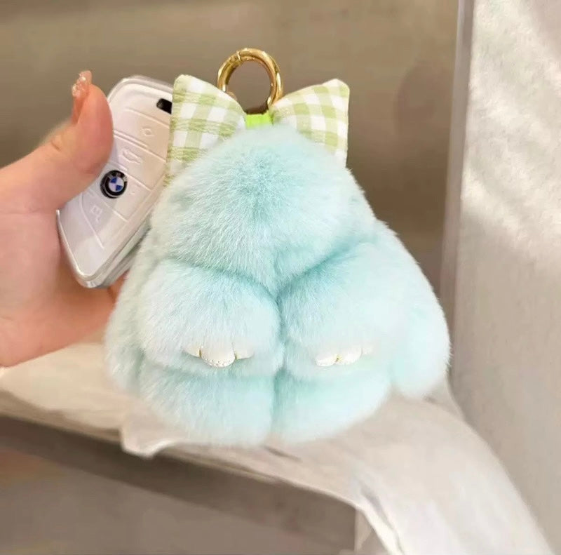 Light blue plush keychain with a bow held over a phone case.